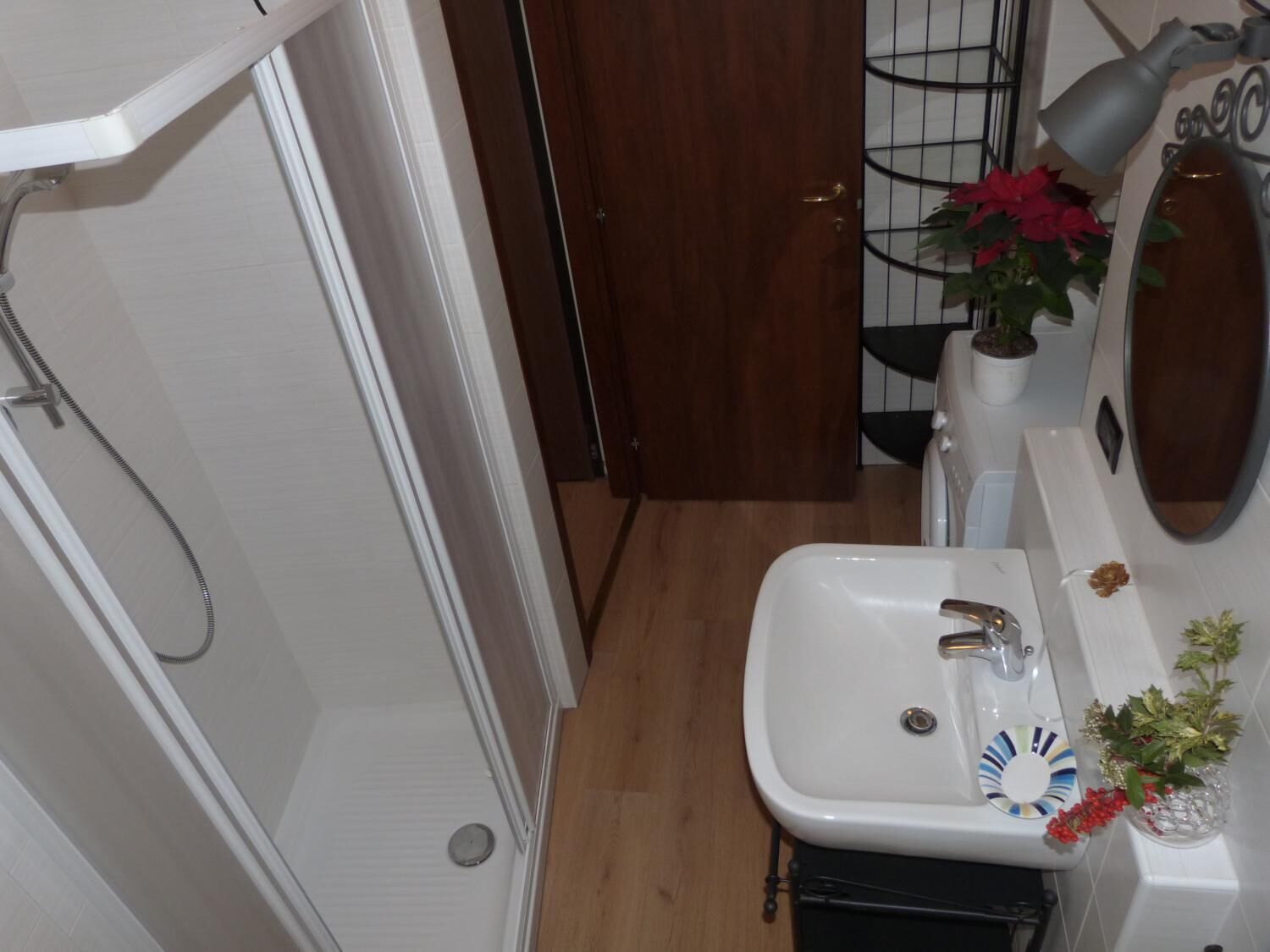 Een badkamer met een douche, wastafel en spiegel.