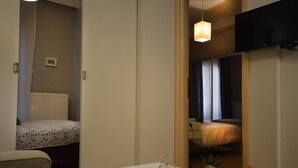 A modern hotel room with a bed, a small table with decorative items, and a television mounted on the wall. - House Loft Foursquare (Thessaloniki)