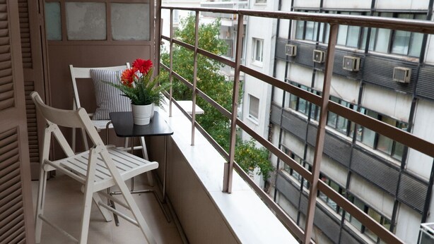 A balcony with a white chair, a small table, and a potted plant. - House Loft Foursquare (Thessaloniki)