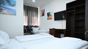 Habitación de hotel con dos camas, un escritorio, una silla, un televisor y obras de arte en la pared.