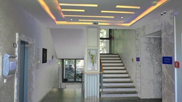Un interior moderno con una escalera, un mostrador de recepción y una planta.