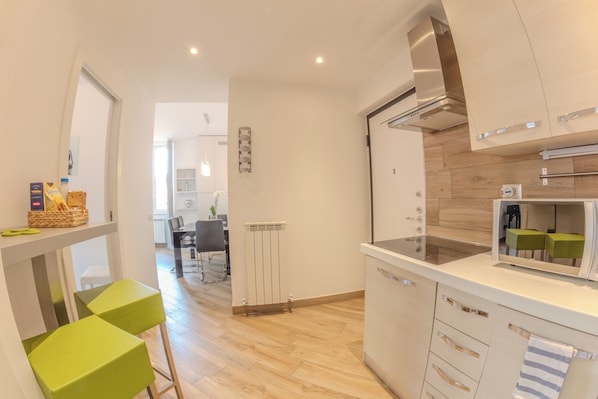Una cocina moderna con microondas integrado, extractor de acero inoxidable y comedor con mesa y sillas.