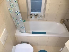 A small bathroom with a bathtub, toilet, and a window. - Apartment Palm Home (Zagreb)