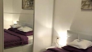 Een slaapkamer met een stapelbed, een nachtkastje met een lamp en een kunstwerk aan de muur.