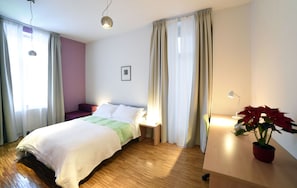 Ein Schlafzimmer mit einem Bett, Nachttisch, Lampe und einem Blumentopf.