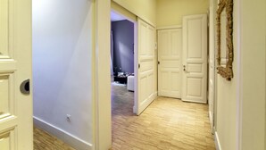 Um corredor com piso de madeira, portas brancas e um espelho na parede.