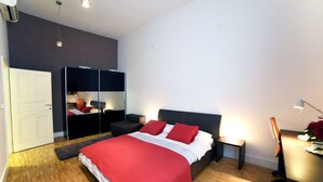 Quarto moderno com uma cama grande, guarda-roupa, escrivaninha e cadeira.
