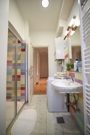 Ein schmales Badezimmer mit Dusche, Toilette und Waschbecken.