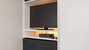 Een televisie op een witte plank met een zwart kastje eronder.