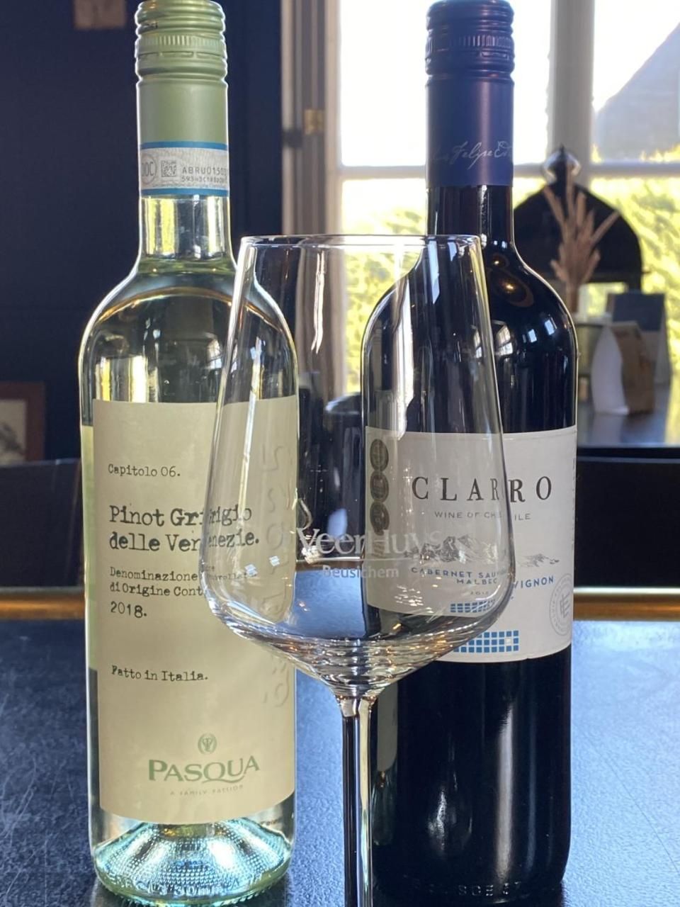 Two wine bottles and a wine glass on a table.