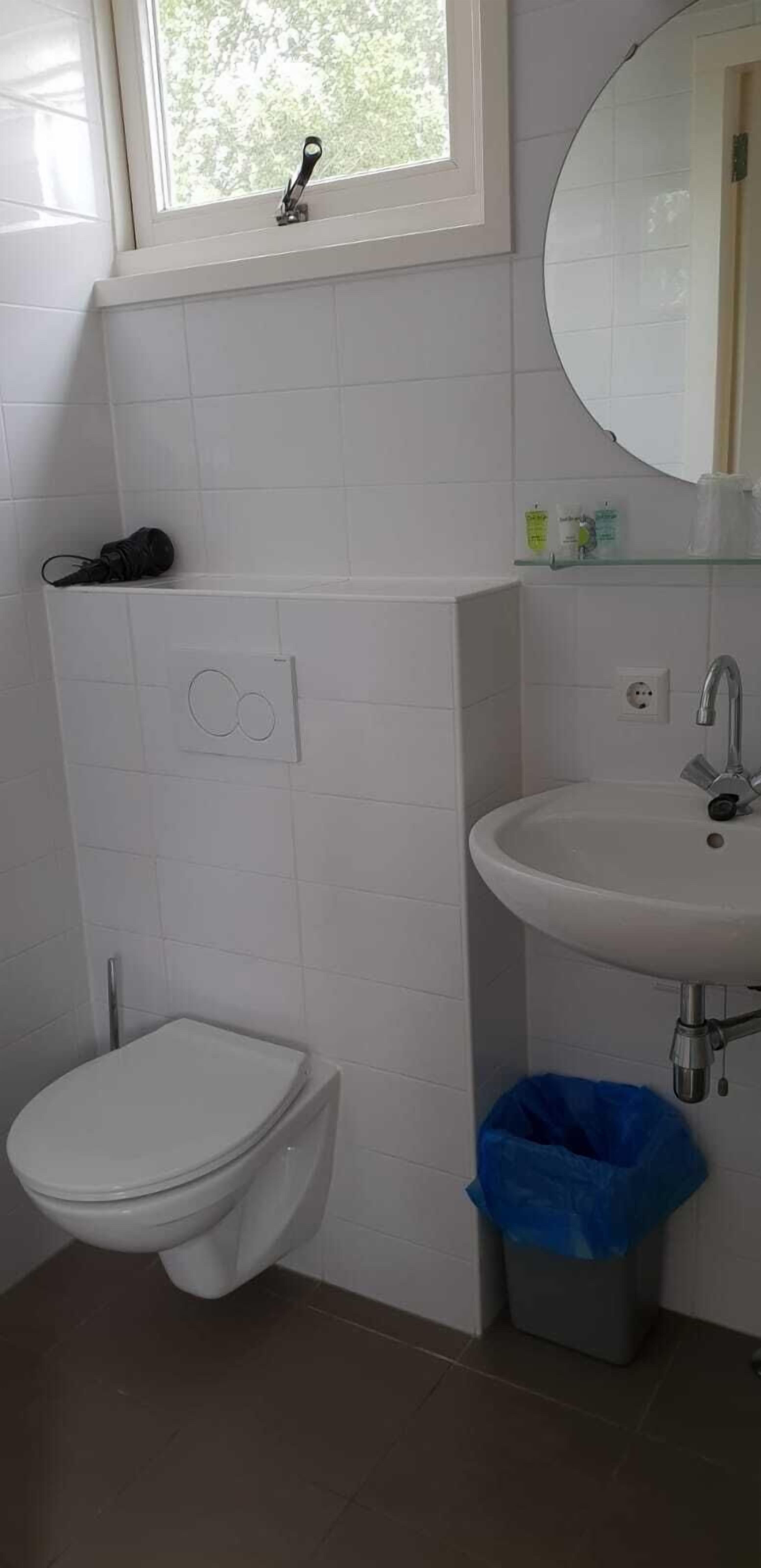 Ein Badezimmer mit Toilette, Waschbecken und Fenster.