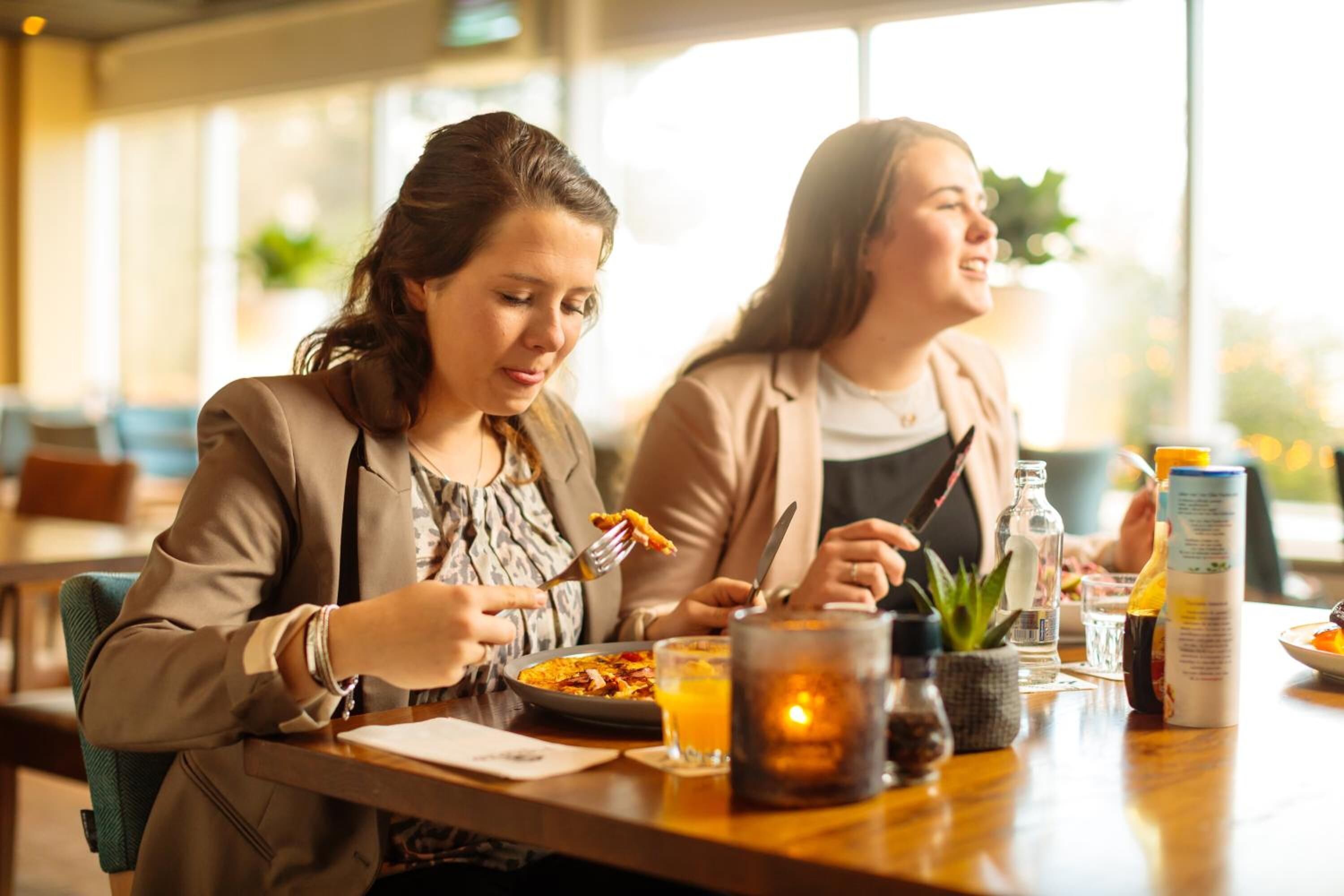 Dos personas cenando en una mesa con una vela, un vaso de agua y una botella de agua.