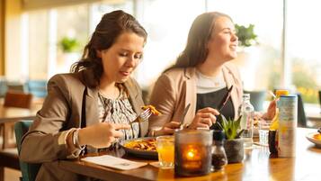 Dos personas cenando en una mesa con una vela, un vaso de agua y una botella de agua.