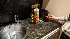 Una cocina con encimera de mármol, pileta de acero inoxidable y cafetera.