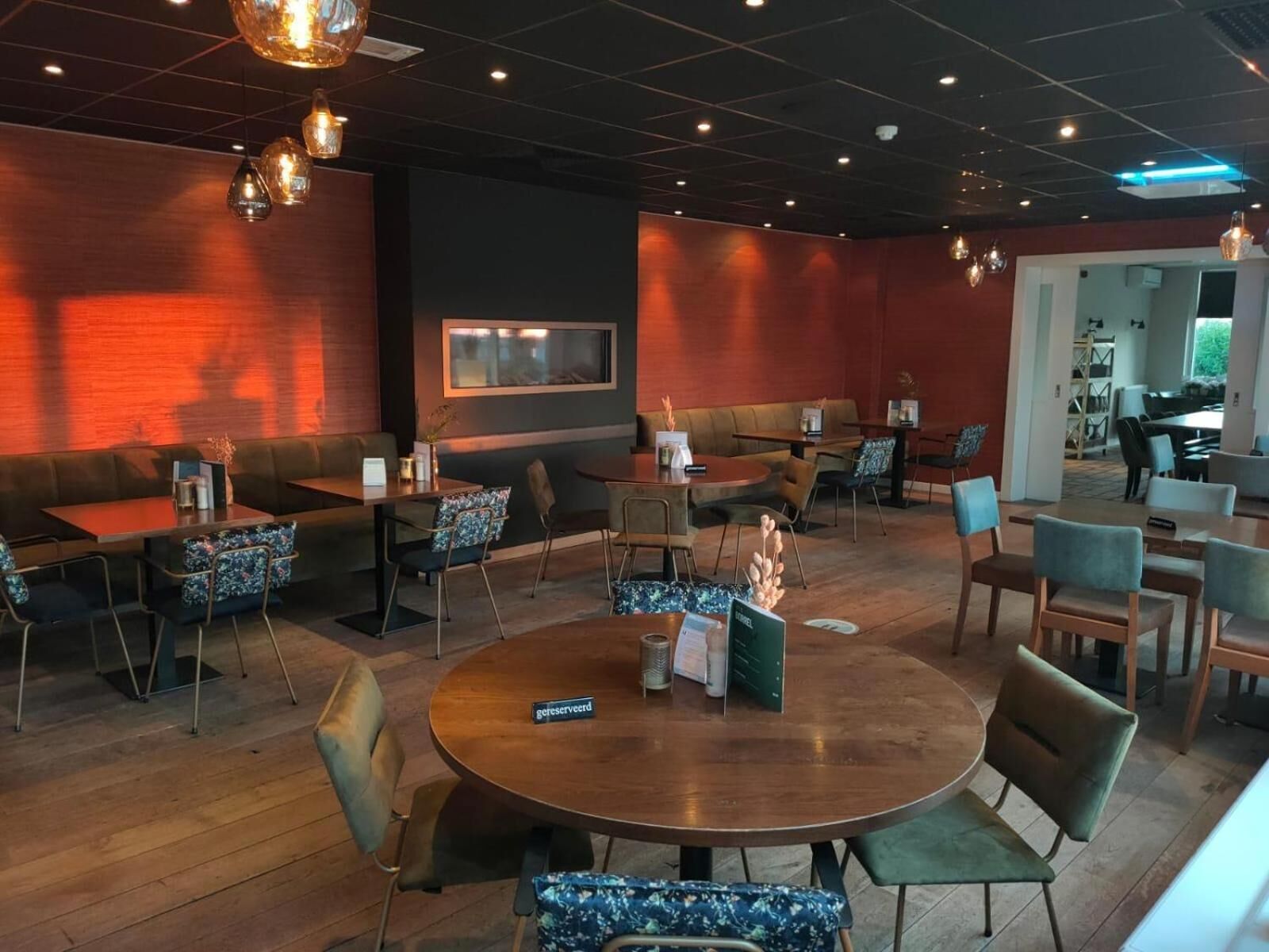 Um restaurante com mesas redondas, cabines e um espaço de bar.