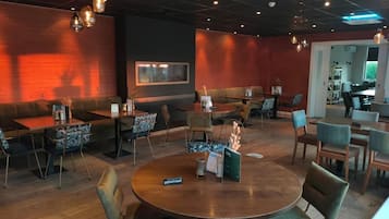 Um restaurante com mesas redondas, cabines e um espaço de bar.