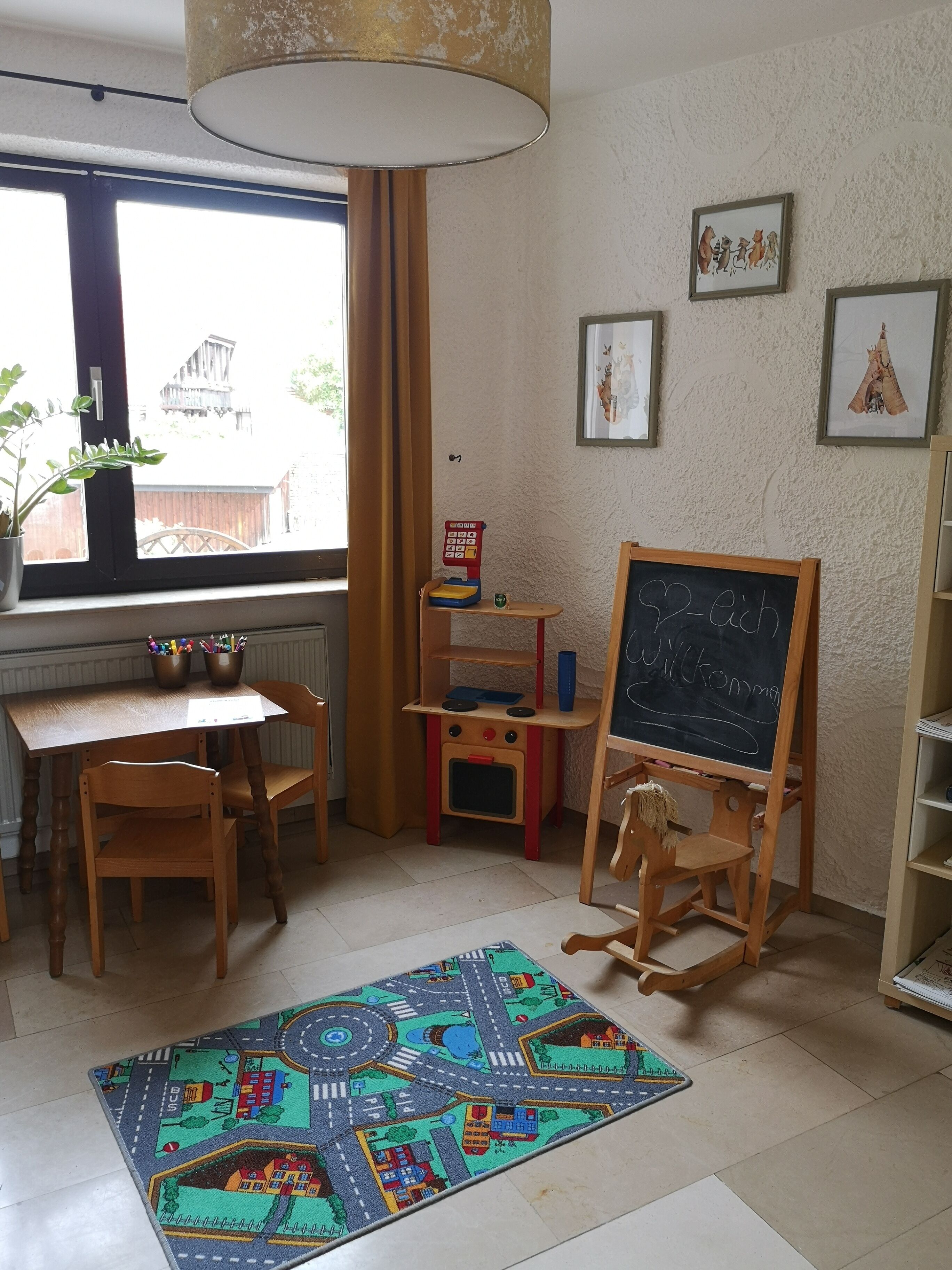 A cozy room with a wooden desk, a chalkboard, a colorful rug, and a window with curtains.