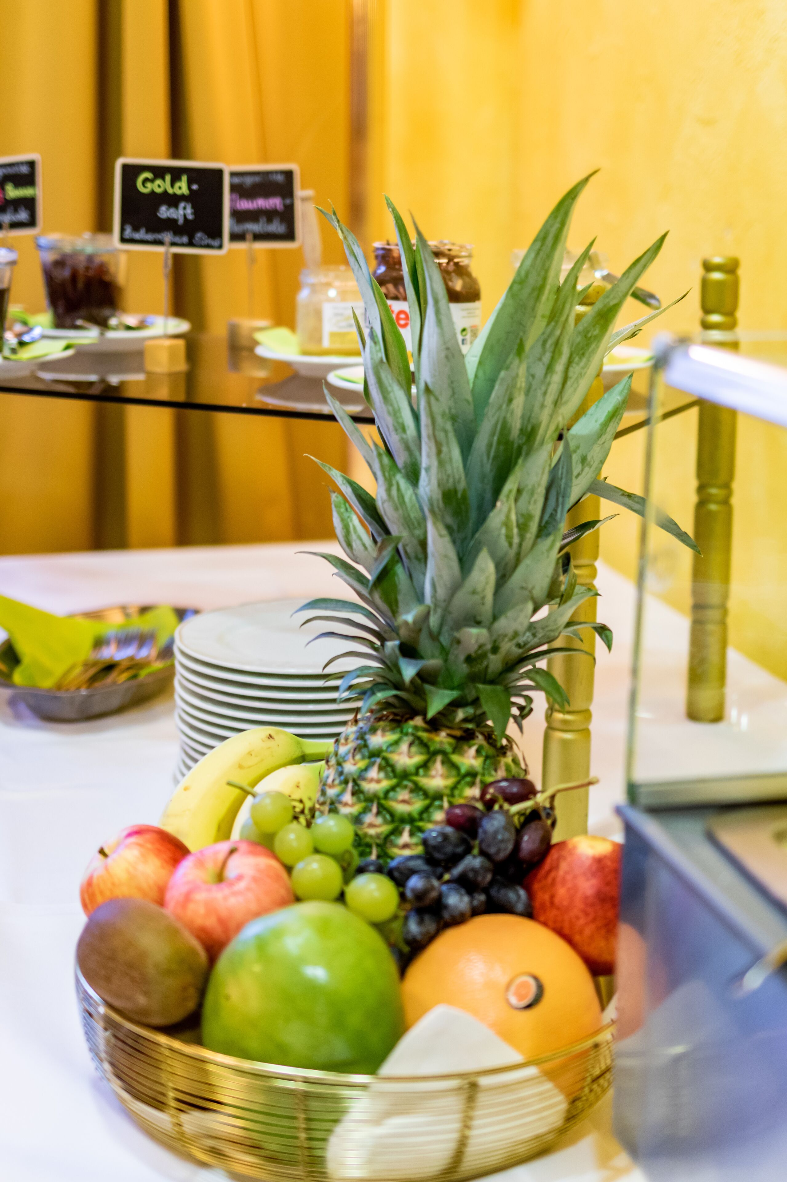A fruit display with a pineapple, apples, grapes, and oranges.
