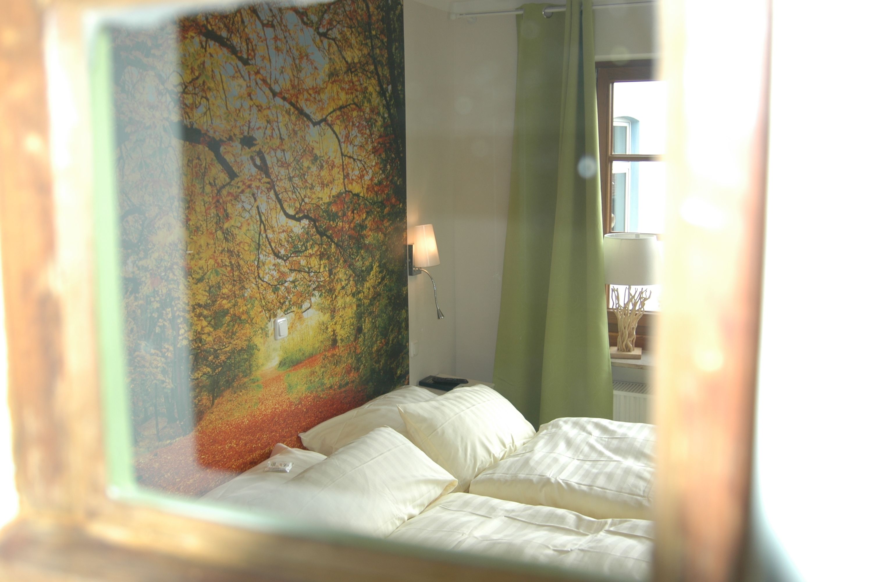 A bedroom with a bed, a wall-mounted lamp, and a window with curtains.