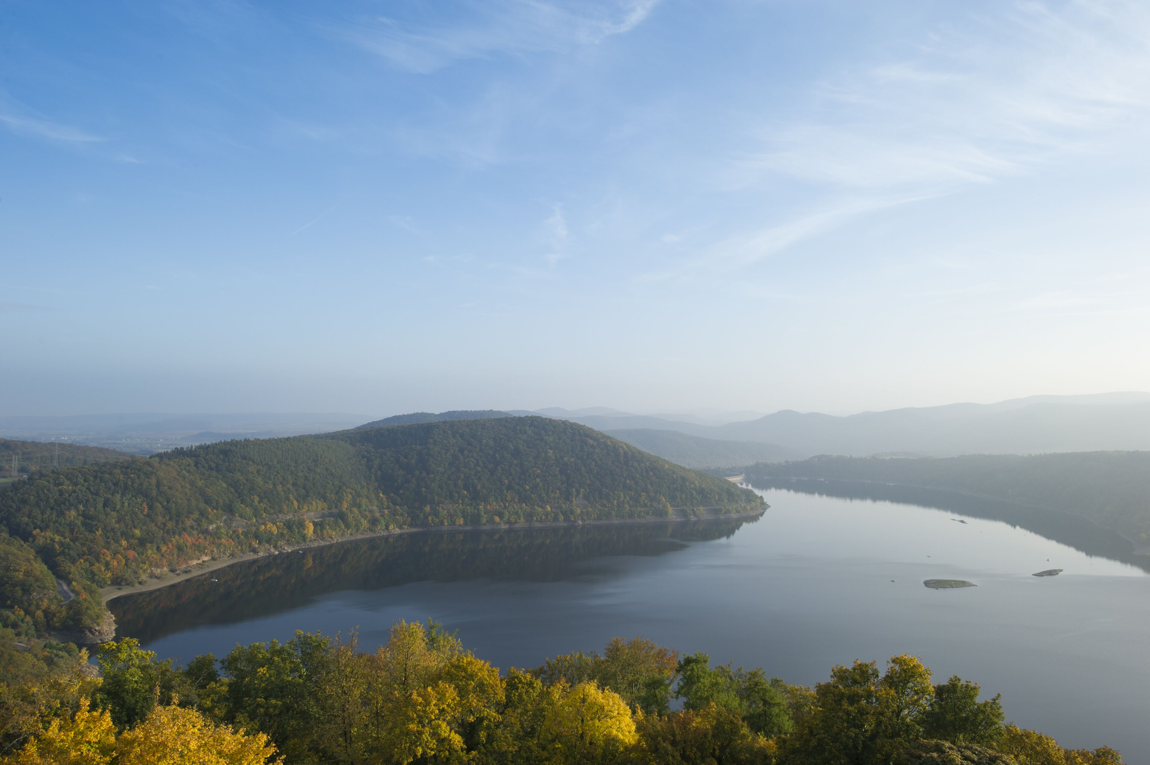 Una vista panorámica de un lago rodeado de colinas boscosas.
