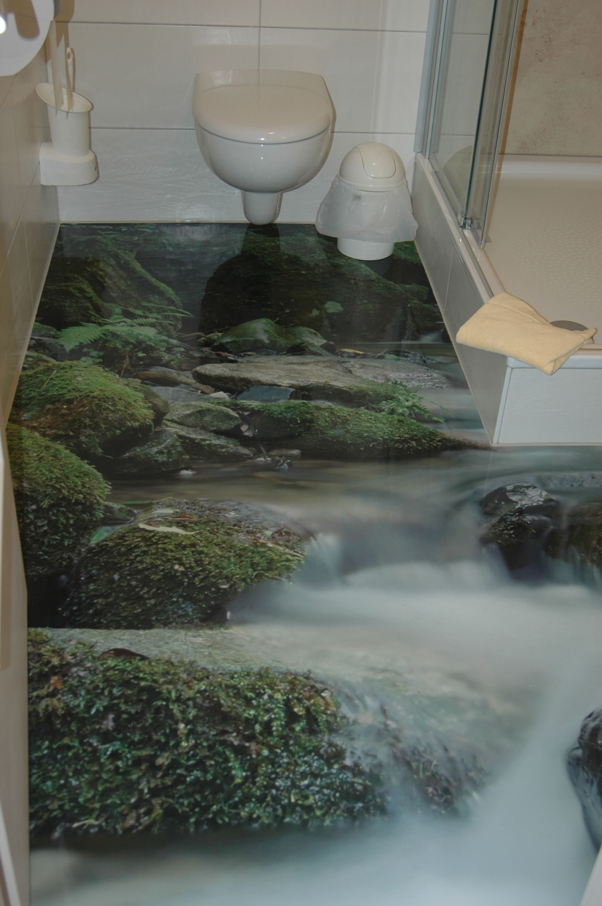 A bathroom with a waterfall design on the floor, a toilet, and a bathtub.