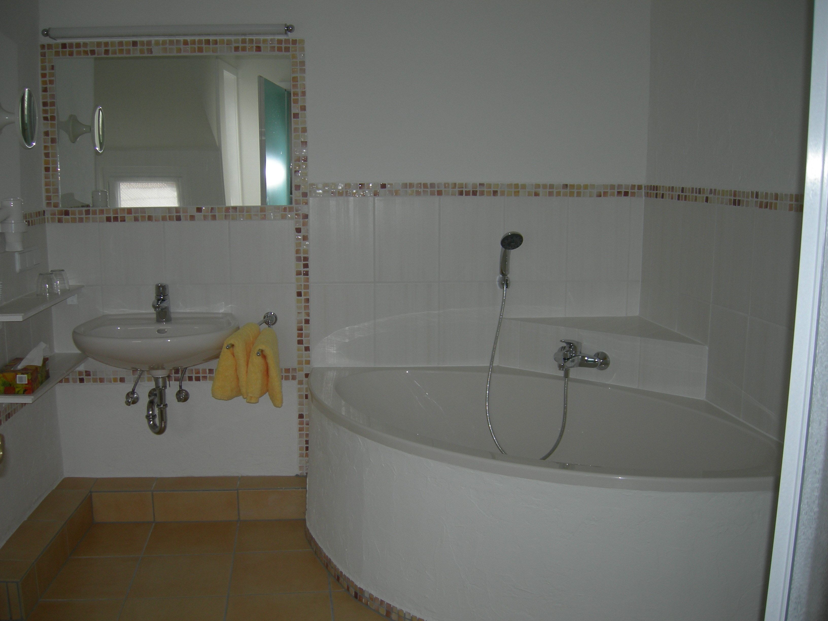 Een badkamer met een wastafel, spiegel en bad.
