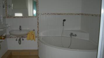 Een badkamer met een wastafel, spiegel en bad.