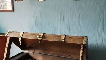 Un cofre de madera con detalles metálicos ornamentales, dos espejos colgados en la pared y un farol antiguo.