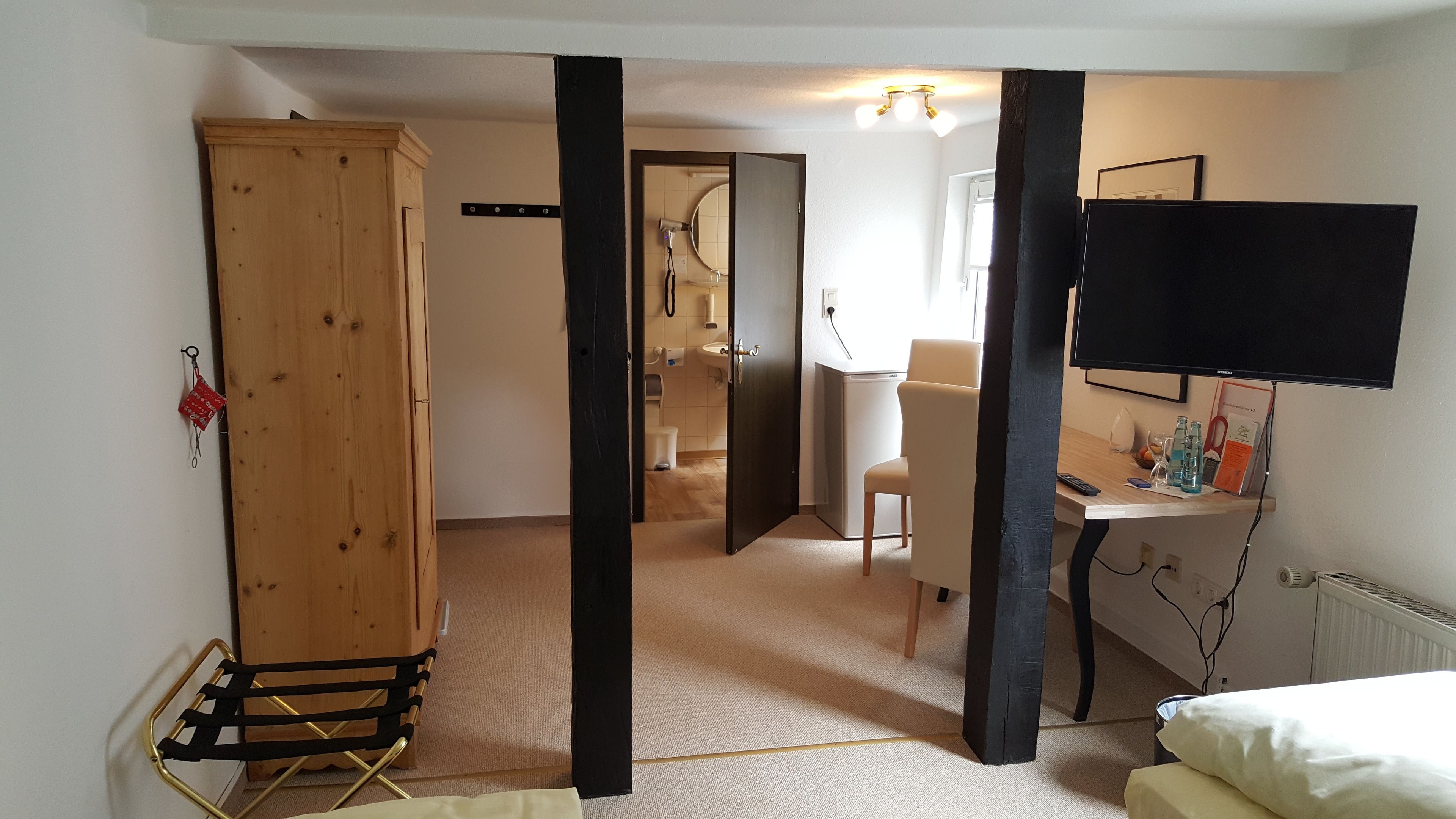 Una habitación con un armario de madera, un escritorio con ordenador, una silla y una cama.