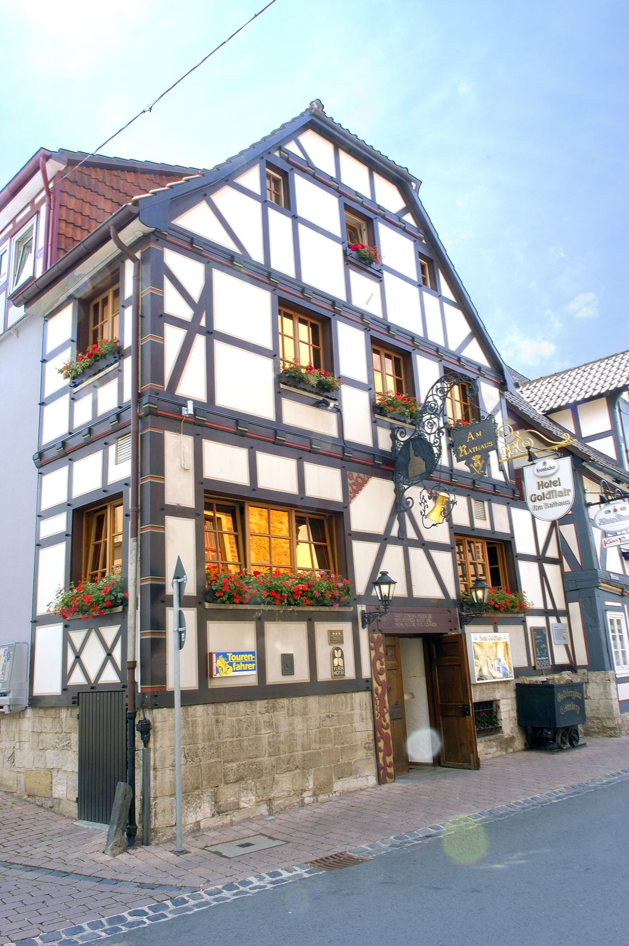 A traditional half-timbered building with multiple windows, flower boxes, and a sign indicating it is a hotel.