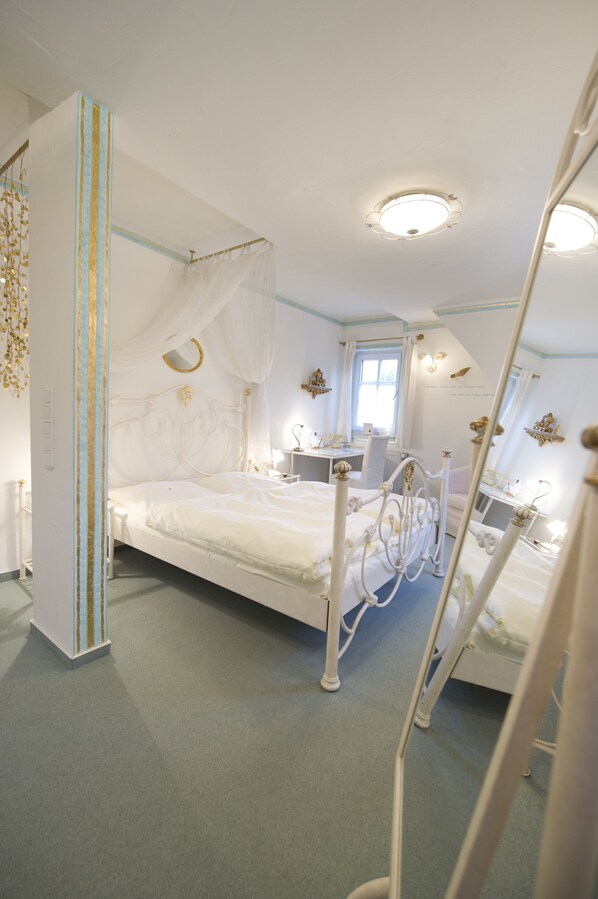 A bedroom with a four-poster bed, a bedside table, a mirror, and a window. - Hotel Goldflair am Rathaus (Korbach)