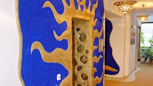 A hallway with a blue and gold wall design, a patterned floor, and a chandelier. - Hotel Goldflair am Rathaus (Korbach)