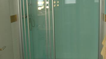 A bathroom with a glass-enclosed shower, a white sink, and a marble-patterned floor.
