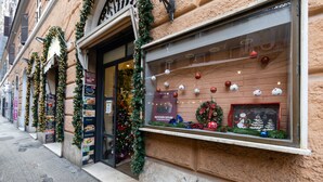 A storefront with a Christmas display including ornaments and a wreath. - TrastevereTop (Rome)