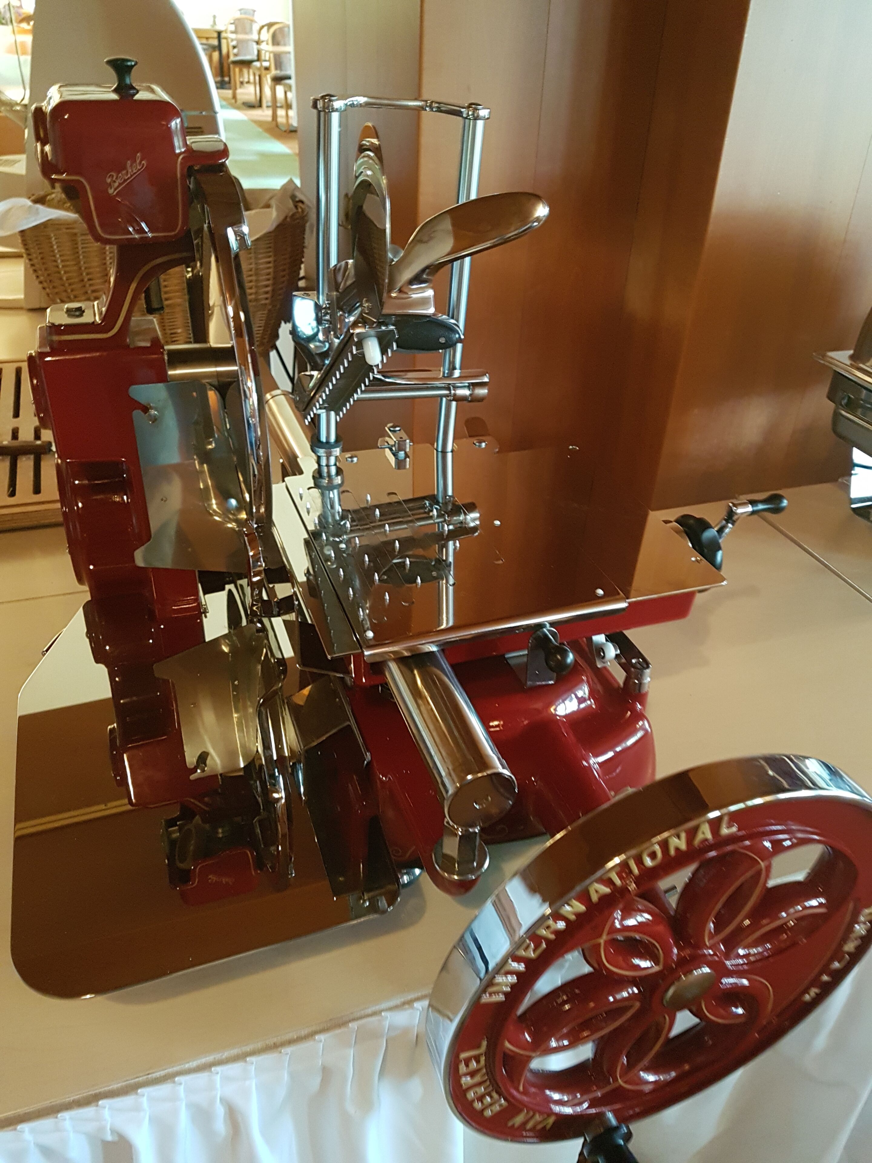 Un appareil mécanique ancien, doté de composants métalliques et d’une base rouge, qui pourrait être un appareil de cuisine d’époque.