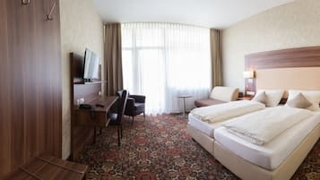 Relax in comfort with a large bed, a seating area, and a desk with a TV.