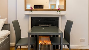 Una habitación con chimenea, una mesa de comedor con sillas, un televisor y un espejo en la pared.