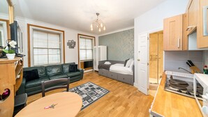 Un espacio habitable compacto con kitchenette, comedor y dormitorio con un ventanal grande.