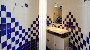 Une salle de bain avec des carreaux bleus et blancs formant un motif à carreaux, un lavabo et des meubles de rangement.
