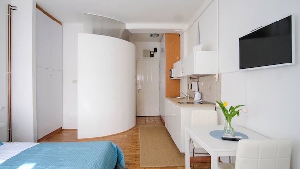 Une chambre d’hôtel compacte comprenant un lit, une petite kitchenette, un coin repas et un téléviseur fixé au mur.