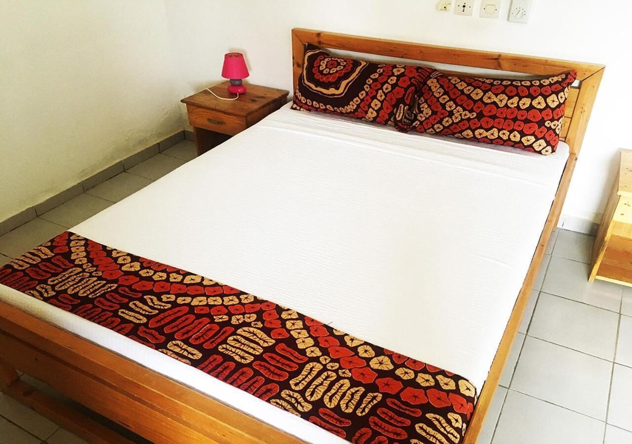 Una cama con una colcha estampada, una mesita de noche con una lámpara y un cabecero de madera.