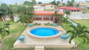 A swimming pool with a surrounding deck, outdoor seating, and palm trees. - Imans Hotel Dabou (Dabou)