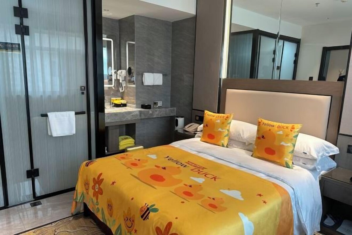 A hotel room with a bed, a bathroom with a mirror, and a nightstand.