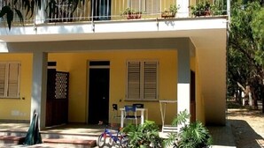 Ein zweistöckiges Gebäude mit Balkon, Topfpflanzen und einem Fahrrad.