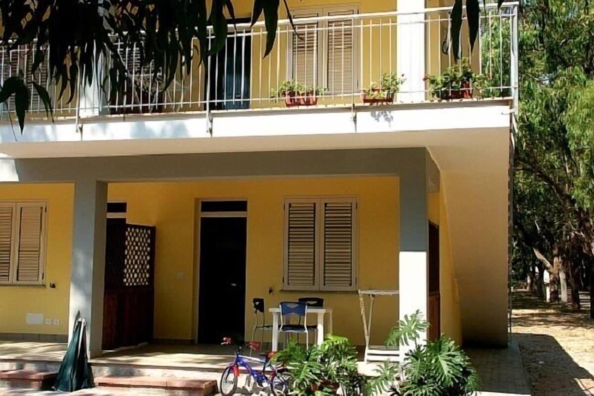 A two-story building with a balcony, potted plants, and a bicycle.