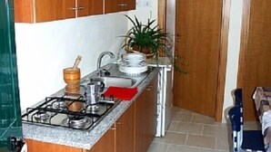 Eine kleine Küche mit Holzausstattung, einem Gasherd, einer Spüle und einer Arbeitsfläche.