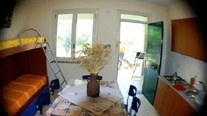 Eine kleine Küche mit Esstisch, einem Fenster und Blick ins Freie.