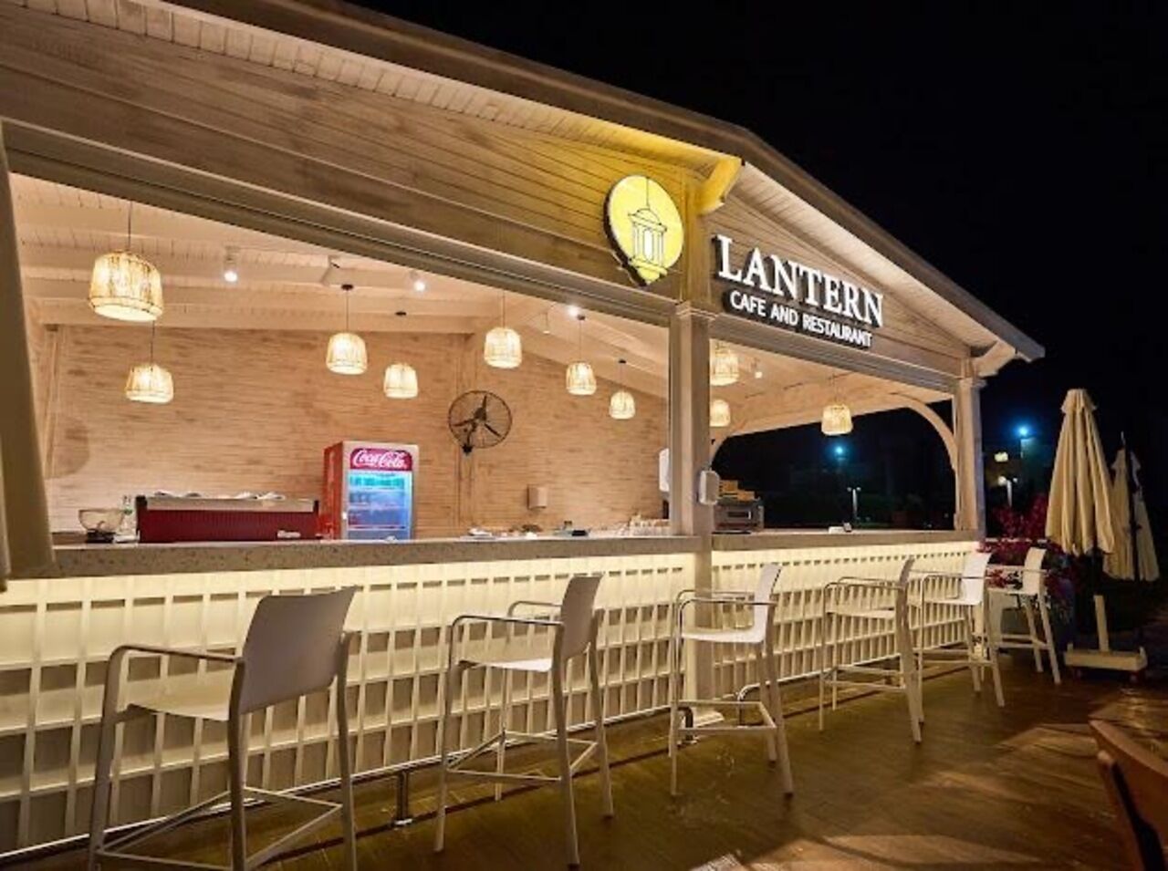 A restaurant named 'Lantern Cafe and Restaurant' with outdoor seating and a Coca-Cola refrigerator.