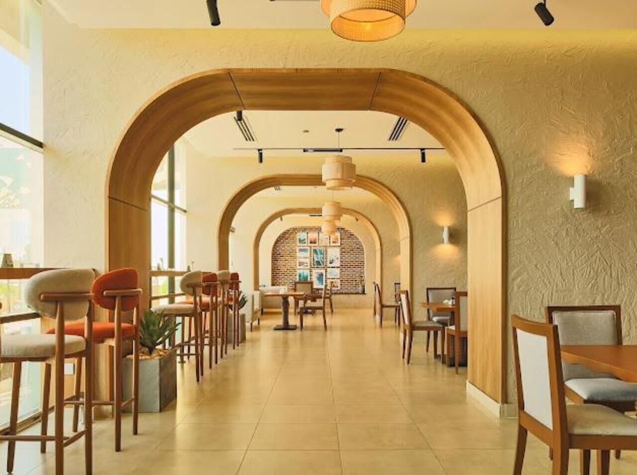 Un amplio pasillo de hotel con arcos de madera, mesas y sillas dispuestas para comer.
