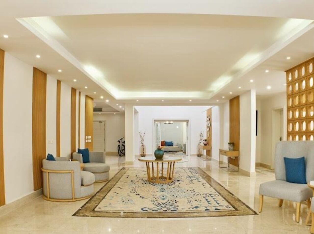A spacious lobby with a central round table, seating arrangements, and a decorative wall.